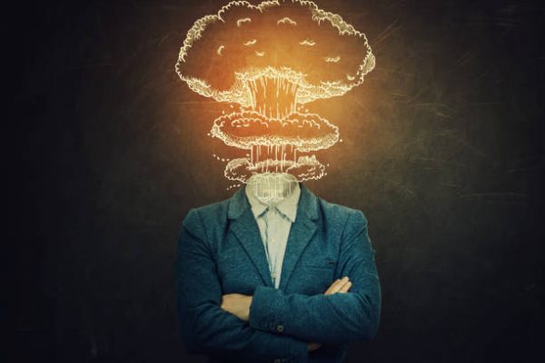 Surreal image nervous man with crossed hands head explosion over blackboard background as nuclear mushroom sketch. Mental state problems, business failure concept. Schizophrenia psychiatric disease.